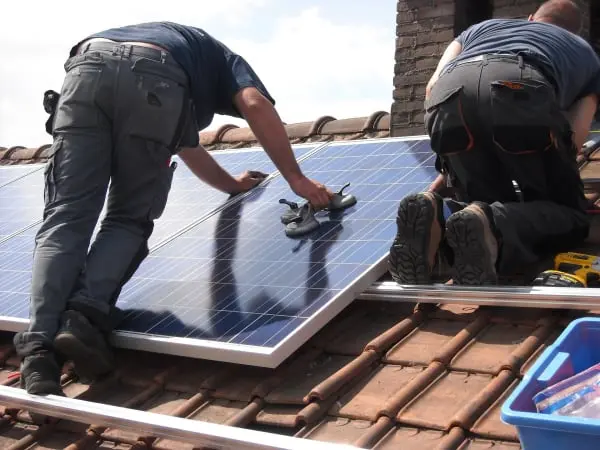 Technicians installing solar panels on a house