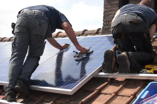 Technicians installing solar panels on a house